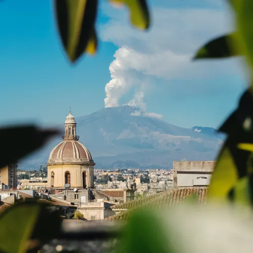 A building with a dome and clouds coming out of it in Catania.